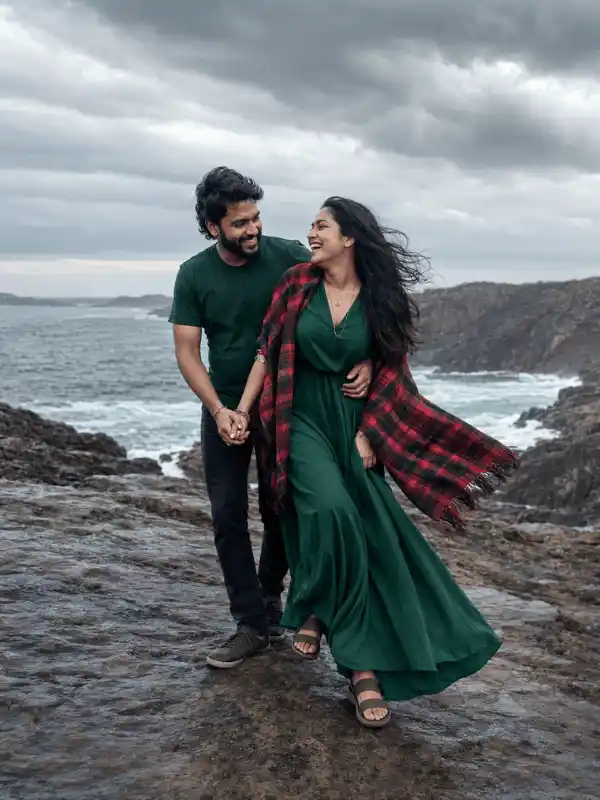 Walking couple hug prompt for Gemini AI on rocky cliffs beside the ocean.